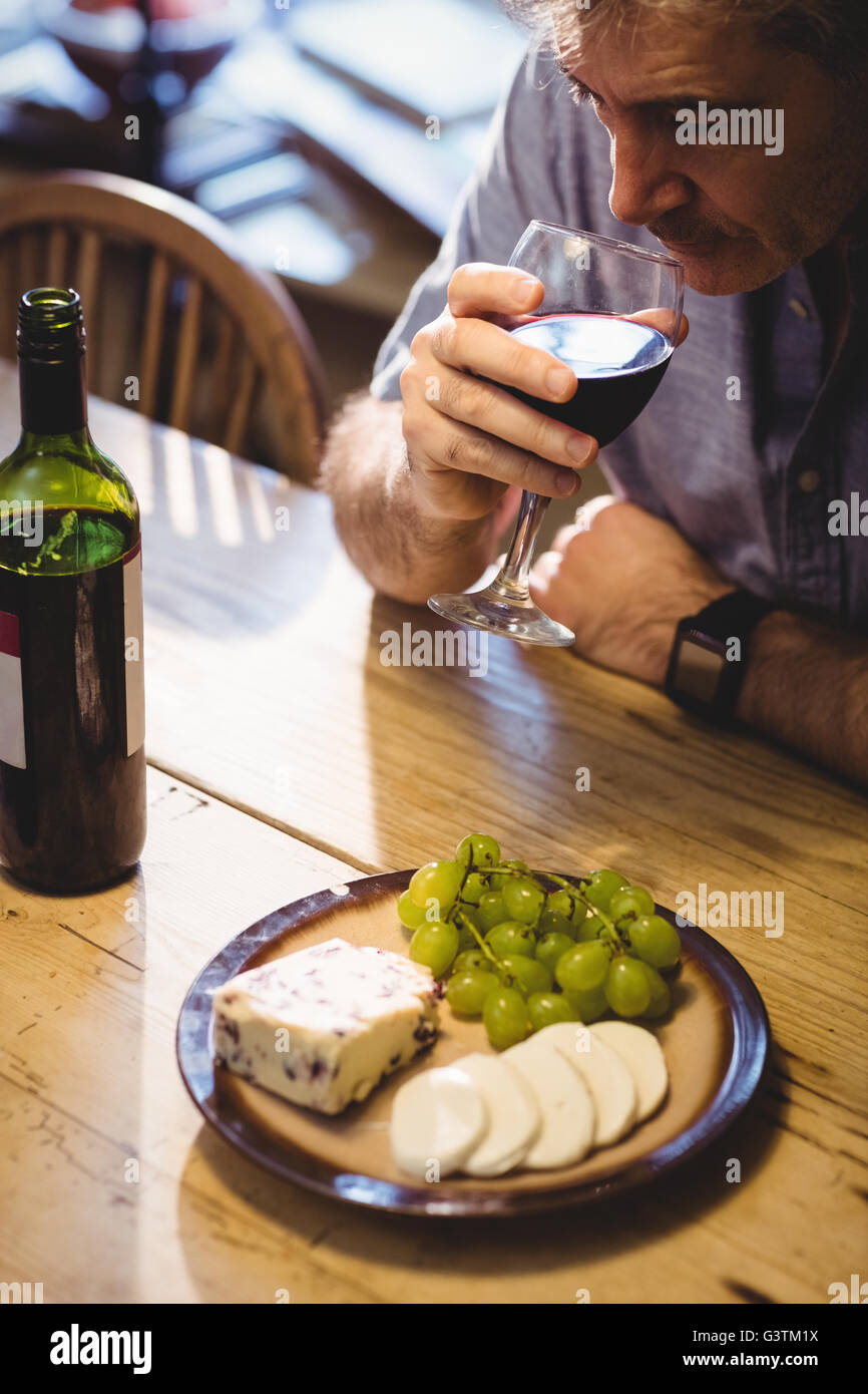 Mature man drinking red wine and eating cheese Stock Photo