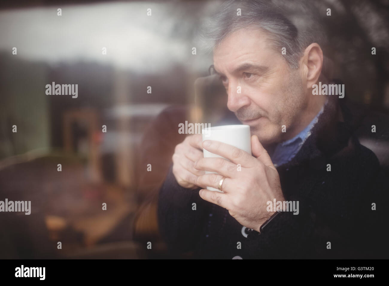 Mature man thinking while looking through window Stock Photo