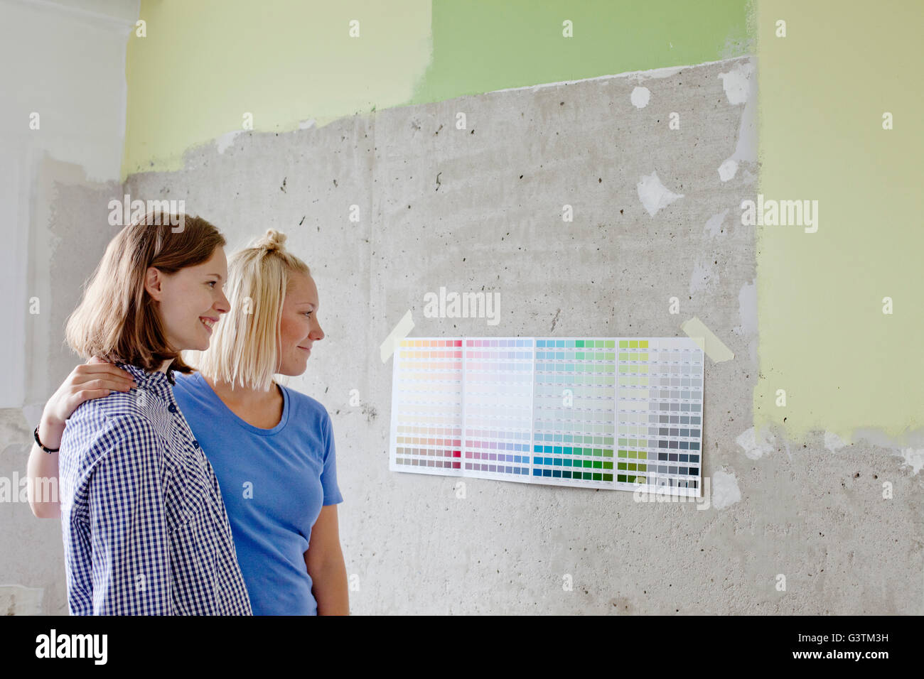 Finland, Young women looking at color swatches attached to wall Stock Photo