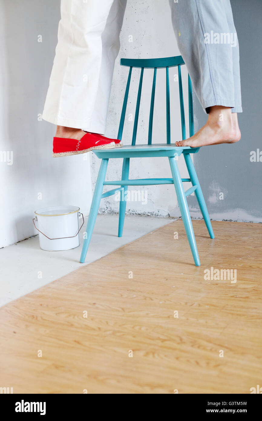 Finland, Women standing on one chair by paint can Stock Photo