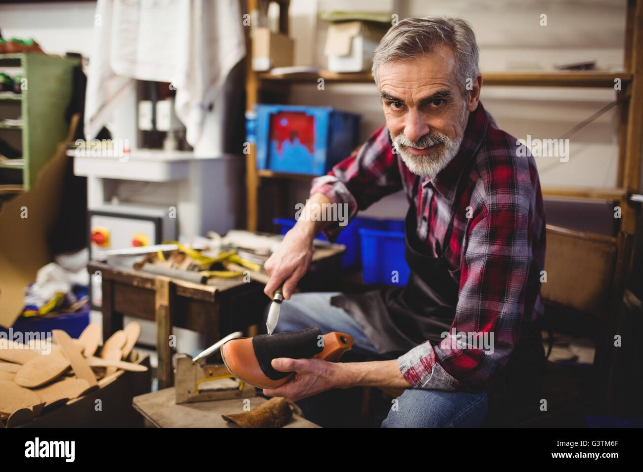 Cobbler smiling and holding a knife and a shoe Stock Photo