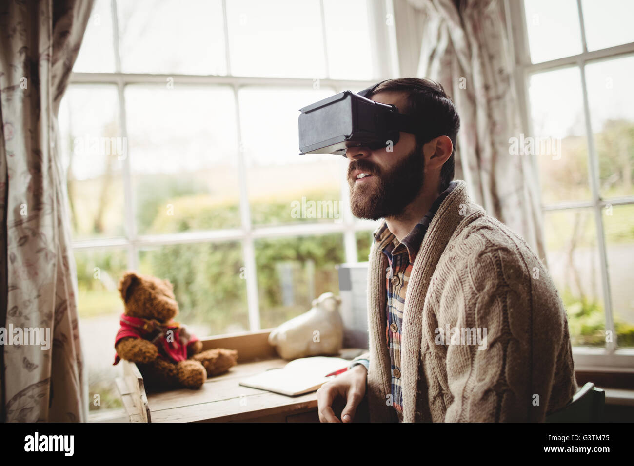 Portrait of hipster man using smart glasses while seating at desk Stock Photo