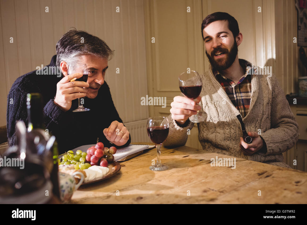 Hipster and mature man having a discussion while drinking red wine Stock Photo