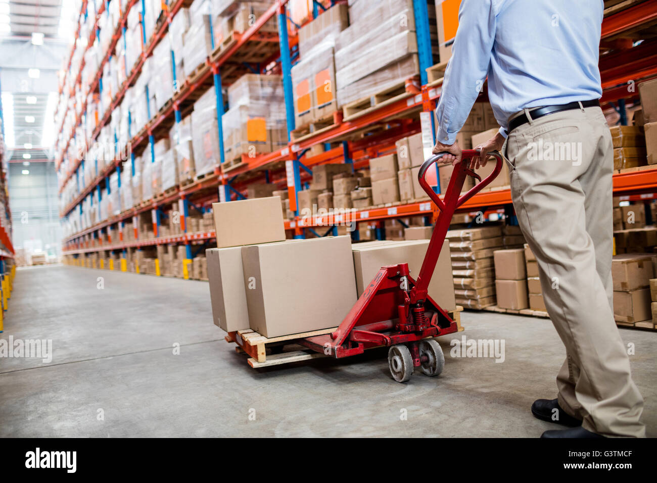 Warehouse manager in aisle with a pallet truck Stock Photo