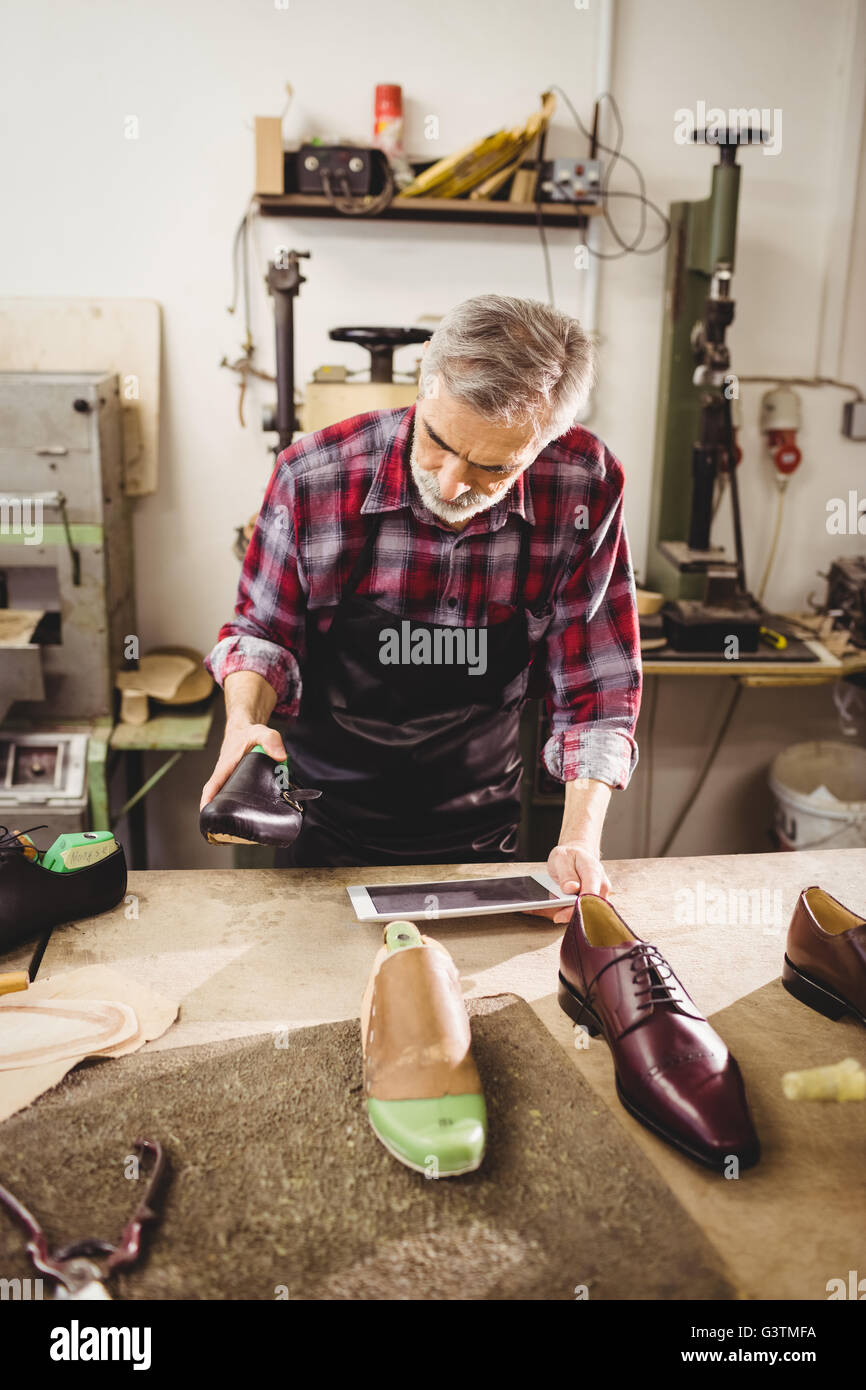 Cobbler holding a shoe and a tablet computer Stock Photo