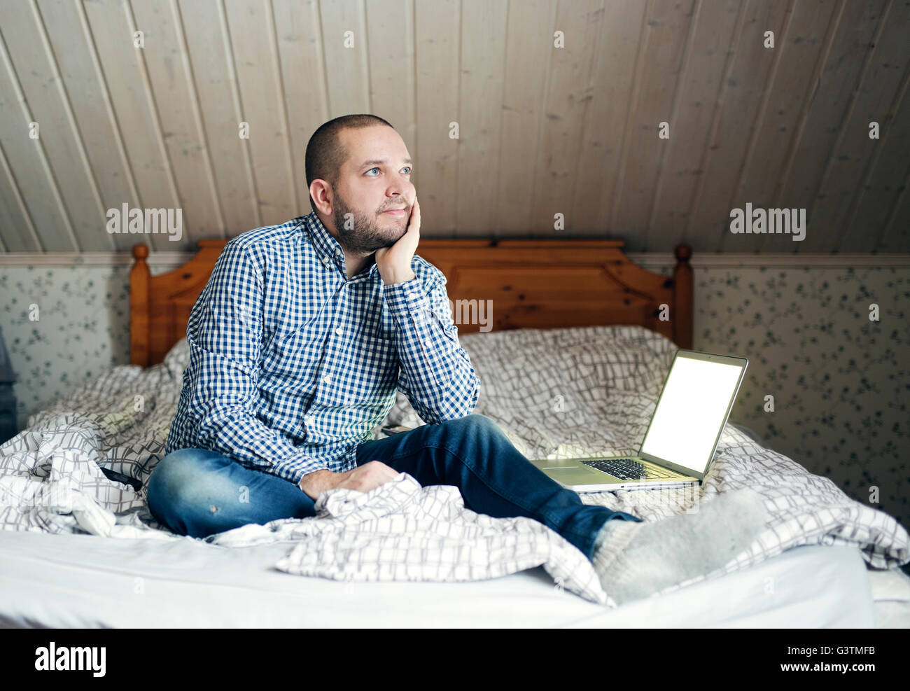 Finland, Man sitting on bed and daydreaming Stock Photo