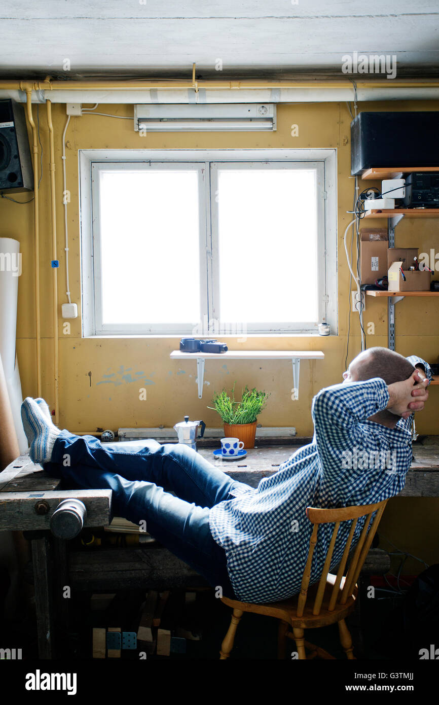 Finland, Man sitting at table with feet up and resting Stock Photo