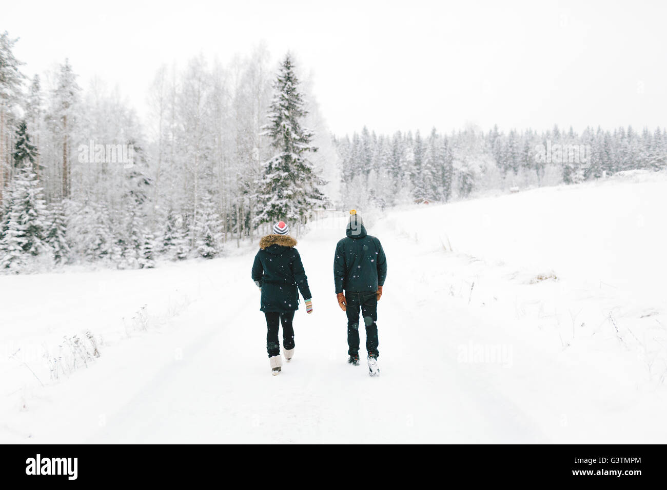 Finland, Jyvaskyla, Saakoski, Young couple walking along road covered with  snow Stock Photo - Alamy