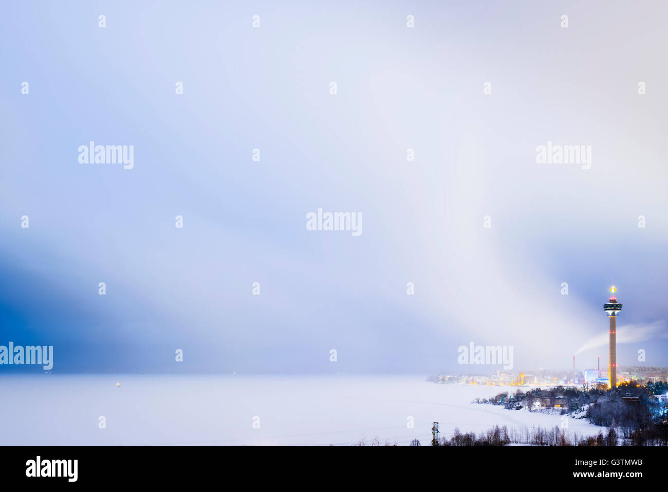 Finland, Pirkanmaa, Tampere, Nasijarvi, Illuminated communications tower over city by lake at dusk Stock Photo