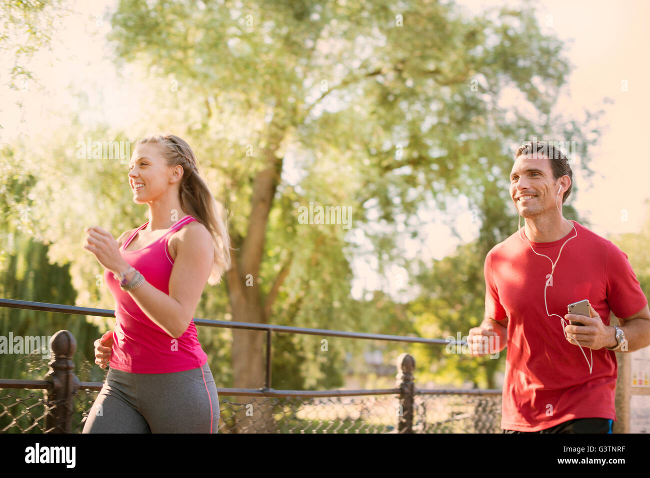 A man and a woman jogging through a park. Stock Photo