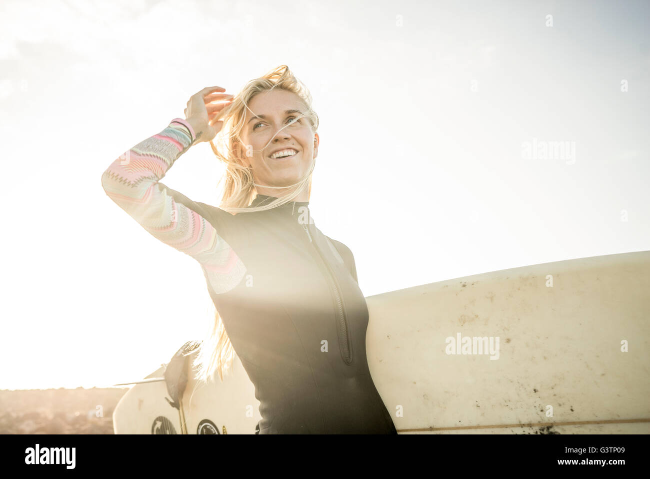 A woman in a wetsuit preparing to surf at Corralejo in Fuerteventura. Stock Photo