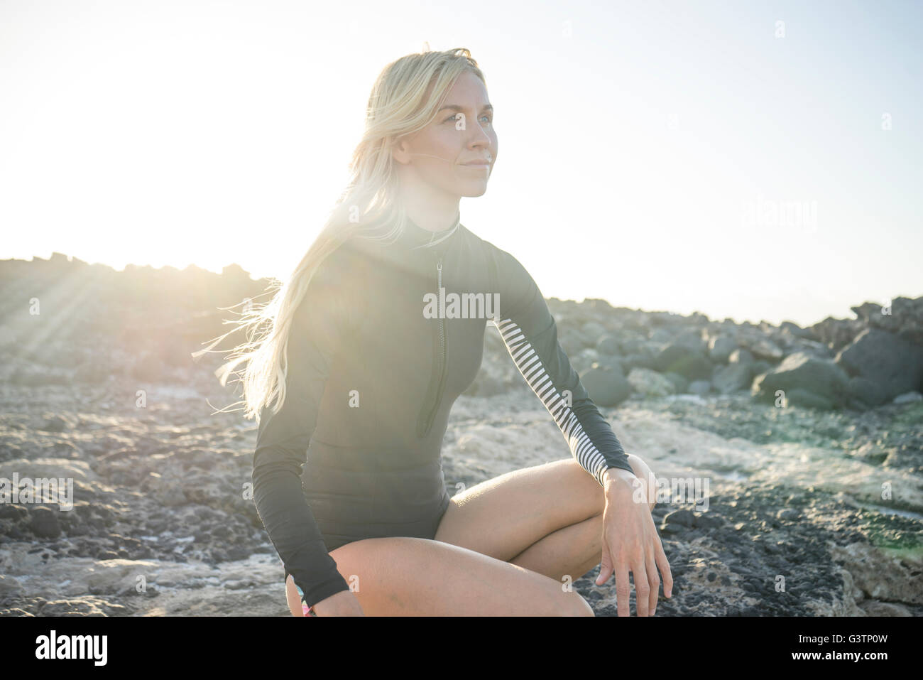 A woman in a wetsuit preparing to surf at Corralejo in Fuerteventura. Stock Photo