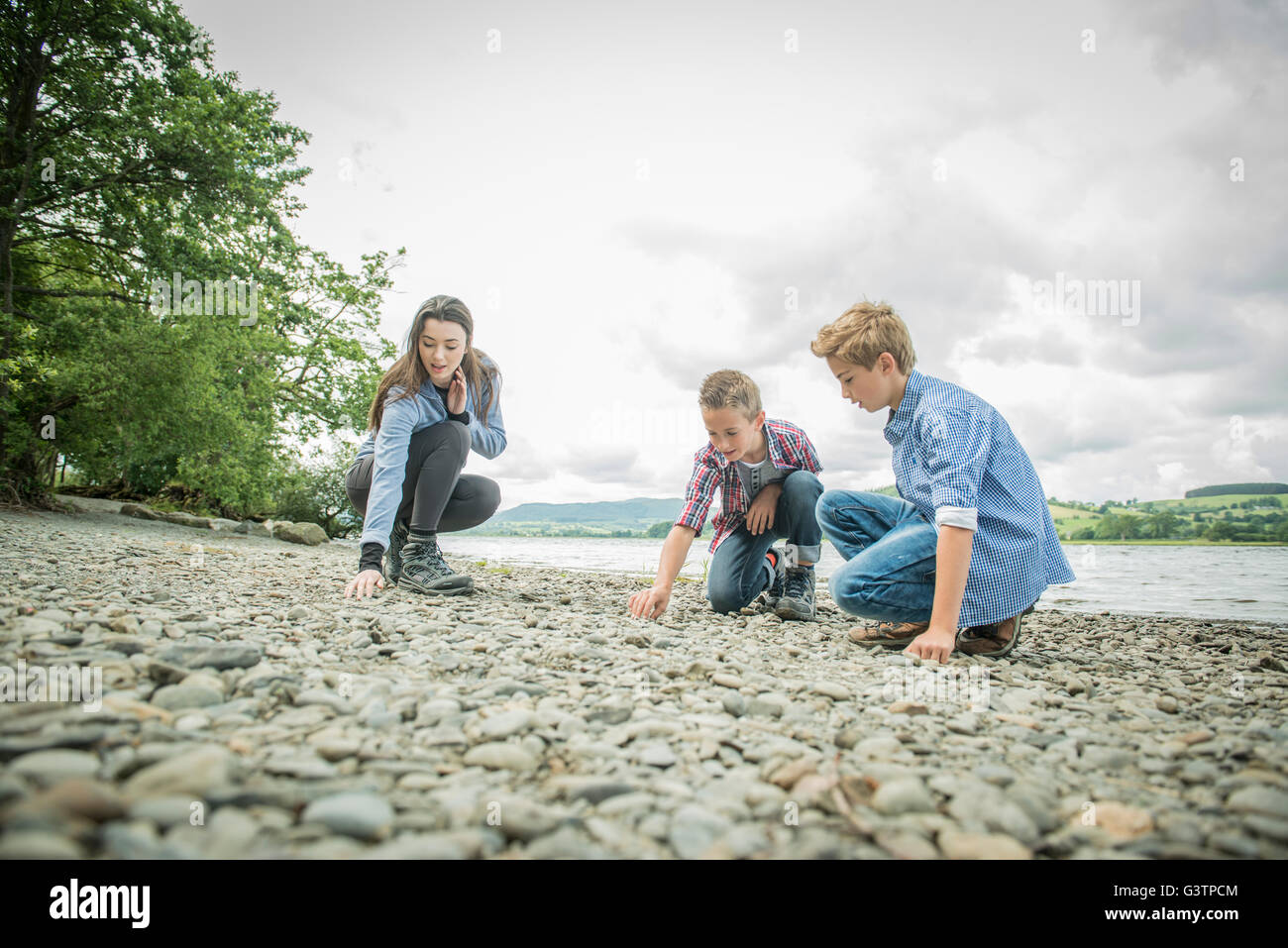 A girl and two boys playing on the shore beside Bala Lake in Wales. Stock Photo