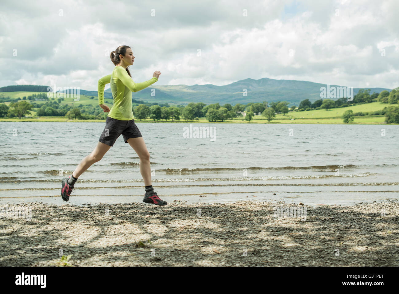 A girl running on the shore beside Bala Lake in Wales. Stock Photo