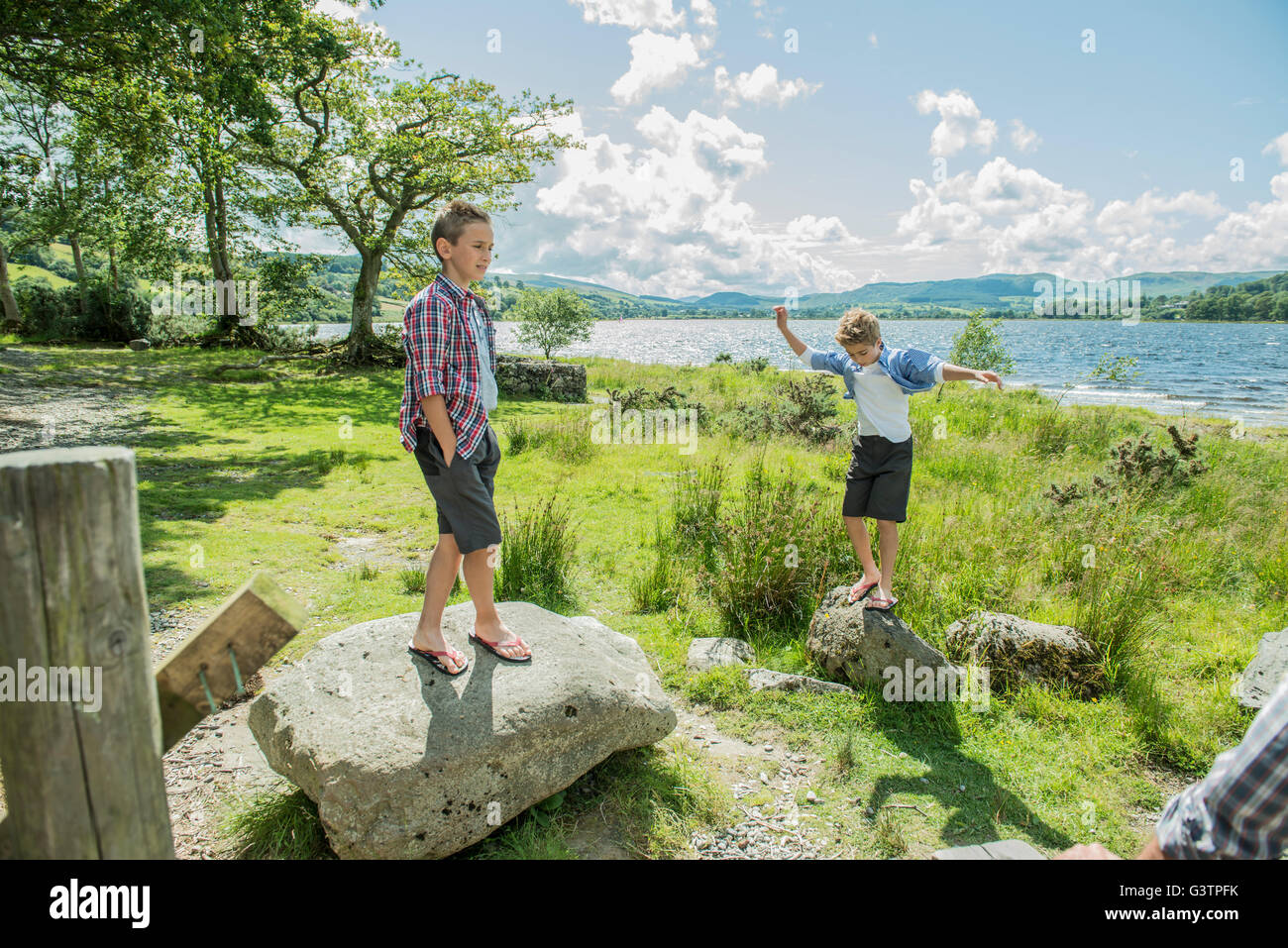 Two boys playing on rocks beside Bala Lake in Wales. Stock Photo