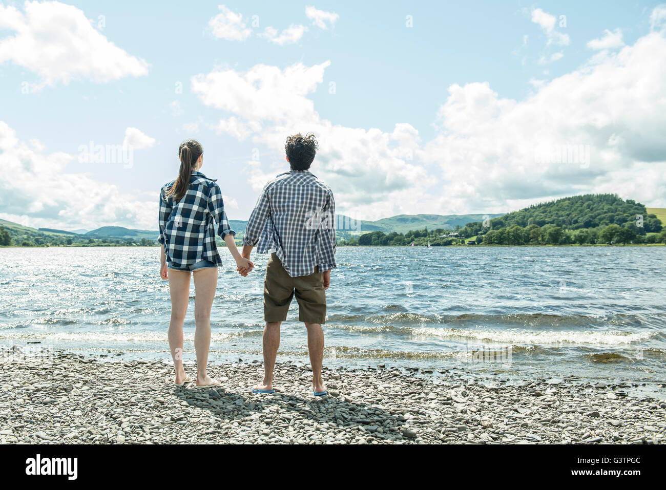 A man and woman standing holding hands on the shore beside Bala Lake in Wales. Stock Photo