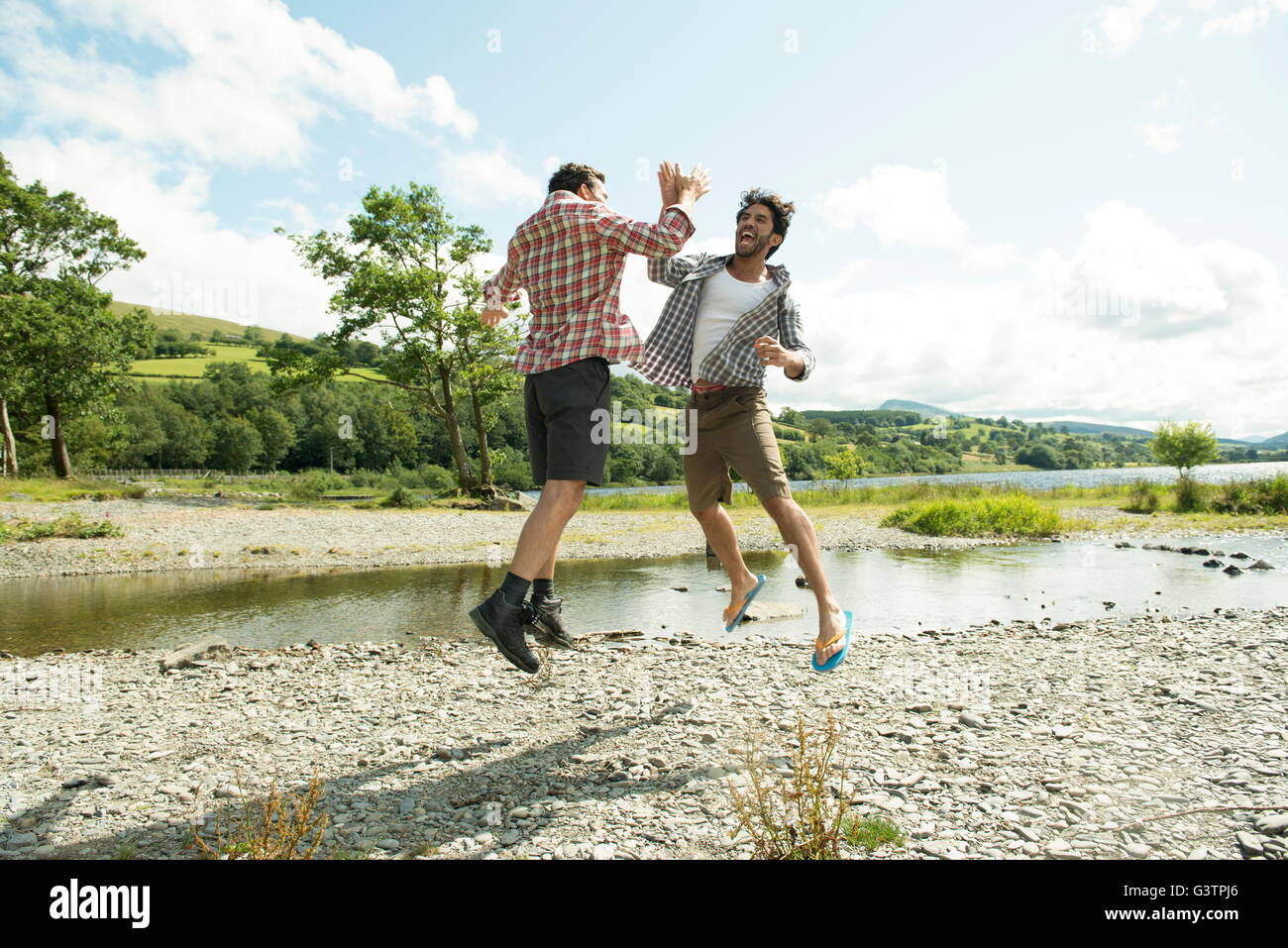 Two men leaping to high five near Bala Lake in Wales Stock Photo - Alamy