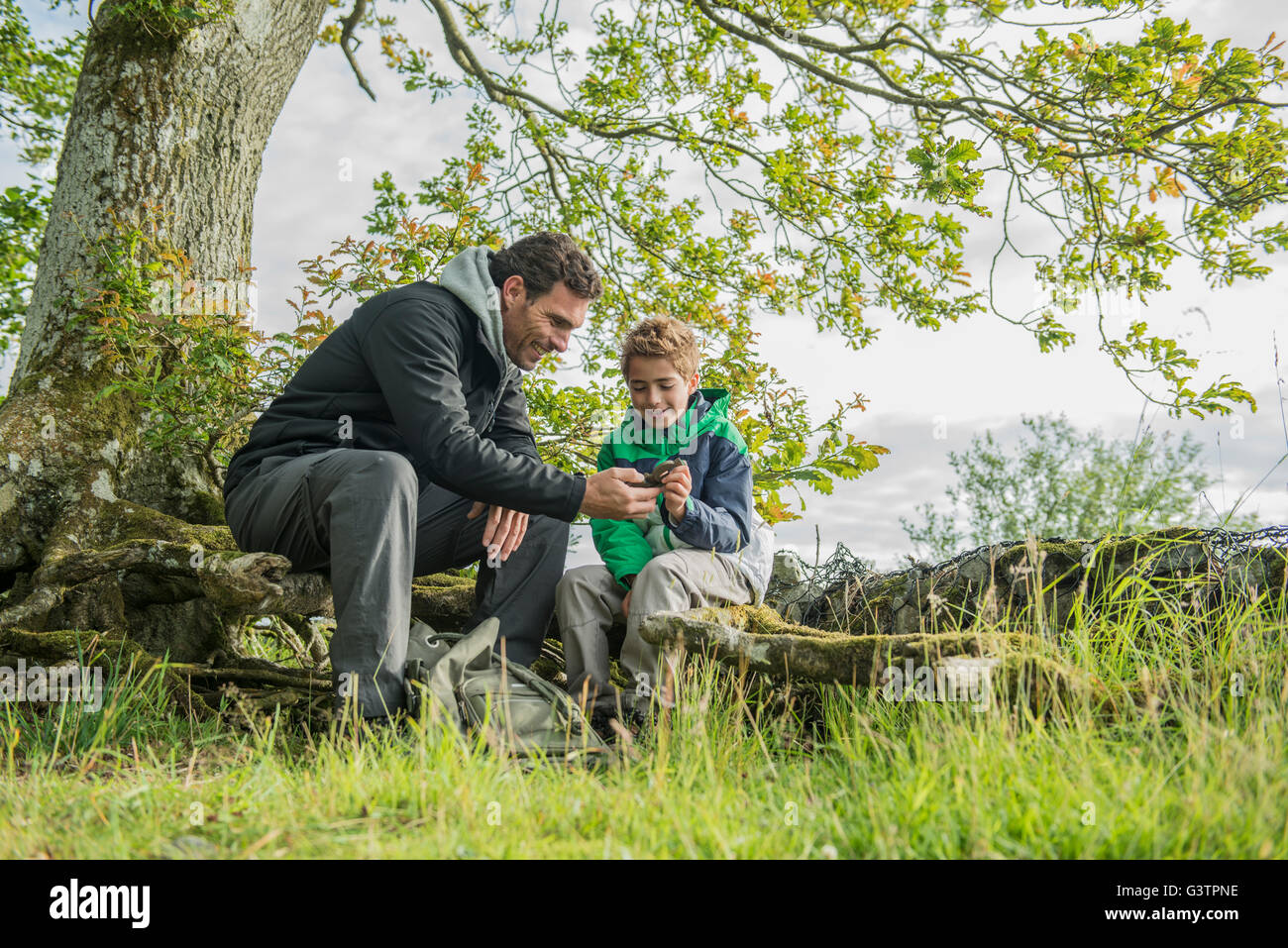 A man showing his son how to use a compass on the shore of Bala Lake in Wales. Stock Photo