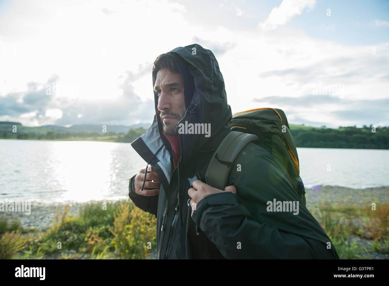 A bearded man in hiking clothes walking on the shore of Bala Lake in Wales. Stock Photo