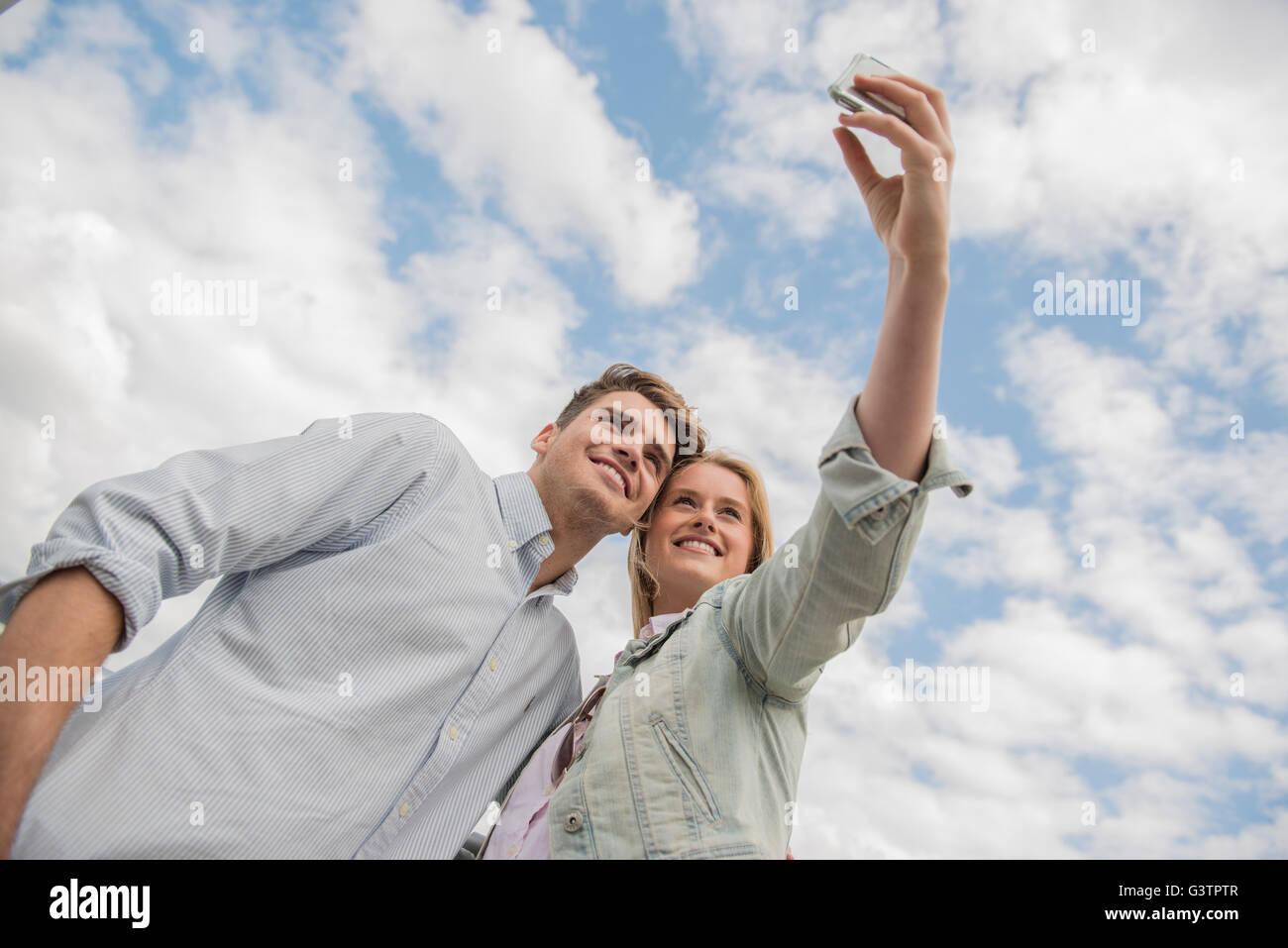 A young couple taking a selfie standing on the Millennium Bridge in London. Stock Photo
