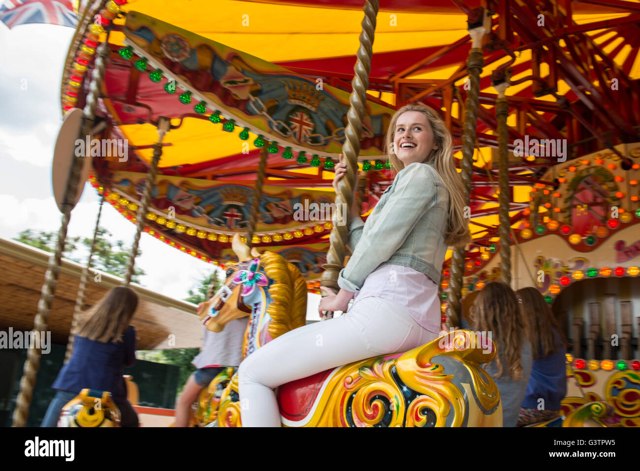 An attractive blond girl riding a carousel on the South Bank in London. Stock Photo