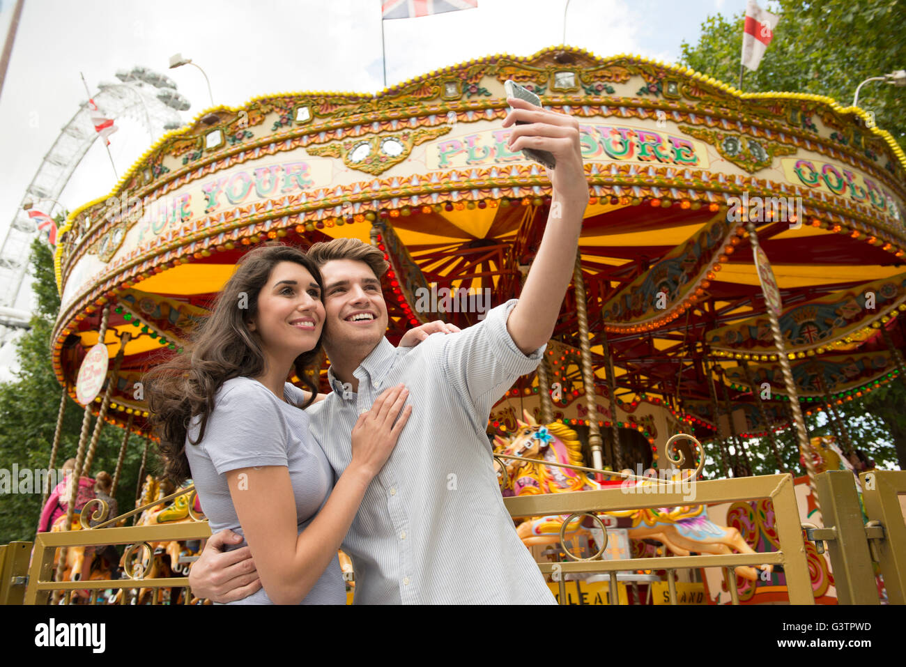 A Young Couple Taking A Selfie In Front Of A Carousel On The South Bank a-young-couple-taking-a-selfie-in-front-of-a-carousel-on-the-south-bank