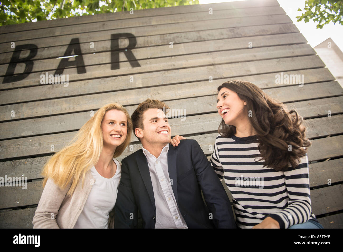 Three friends sitting on a bench on the South Bank in London. Stock Photo