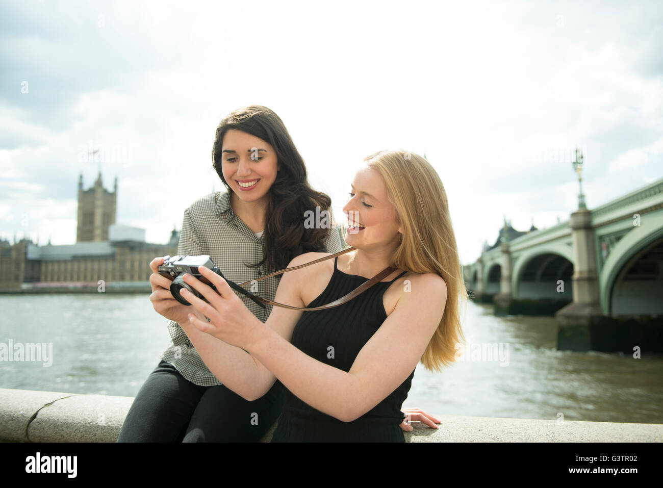 Two friends taking photographs on the South Bank in London with the Houses of Parliament in the background. Stock Photo