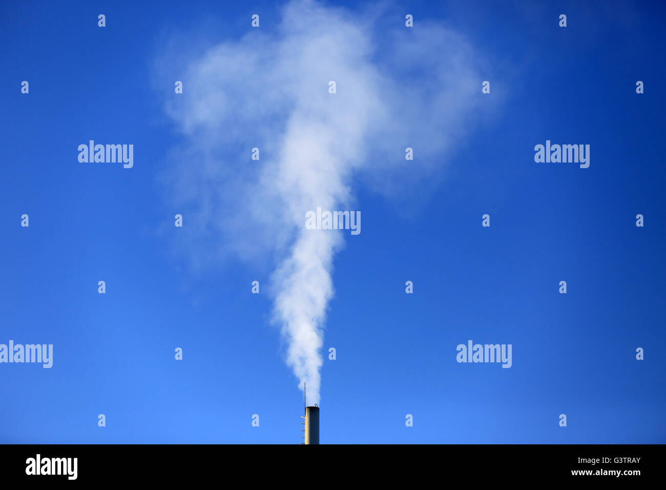Flue and smoke against blue sky background Stock Photo