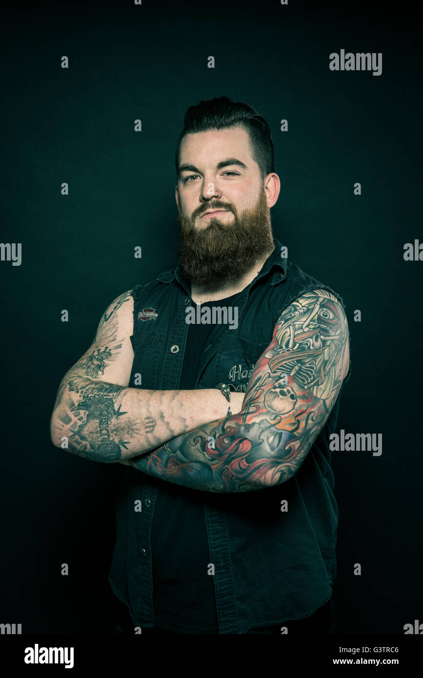 Studio portrait of a bearded man with tattooed arms Stock Photo - Alamy