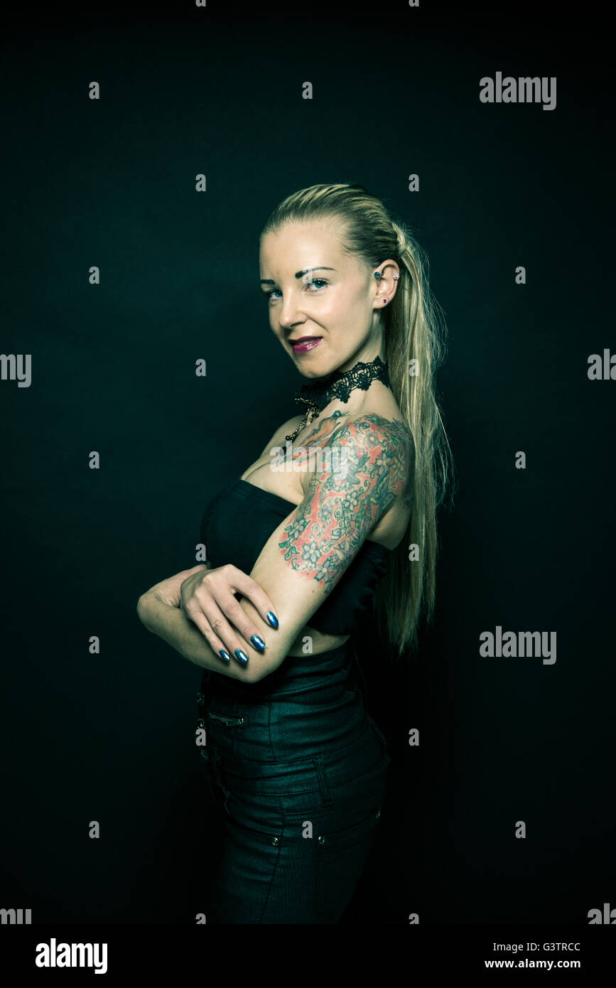 Studio portrait of a young woman with tattooed arms. Stock Photo