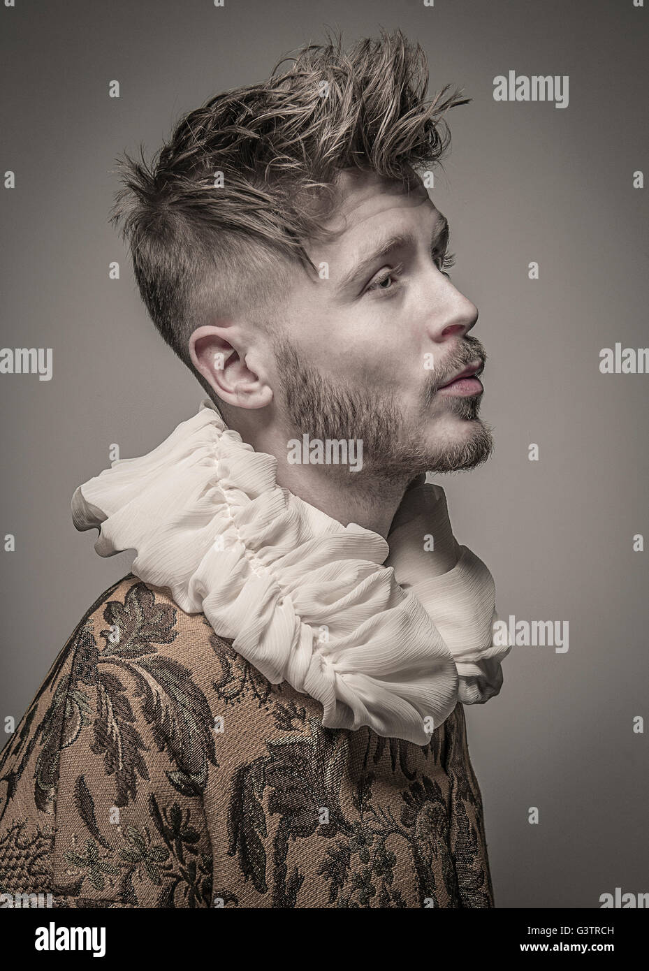 Studio portrait of a young man in profile wearing a jacket with a frilled collar. Stock Photo