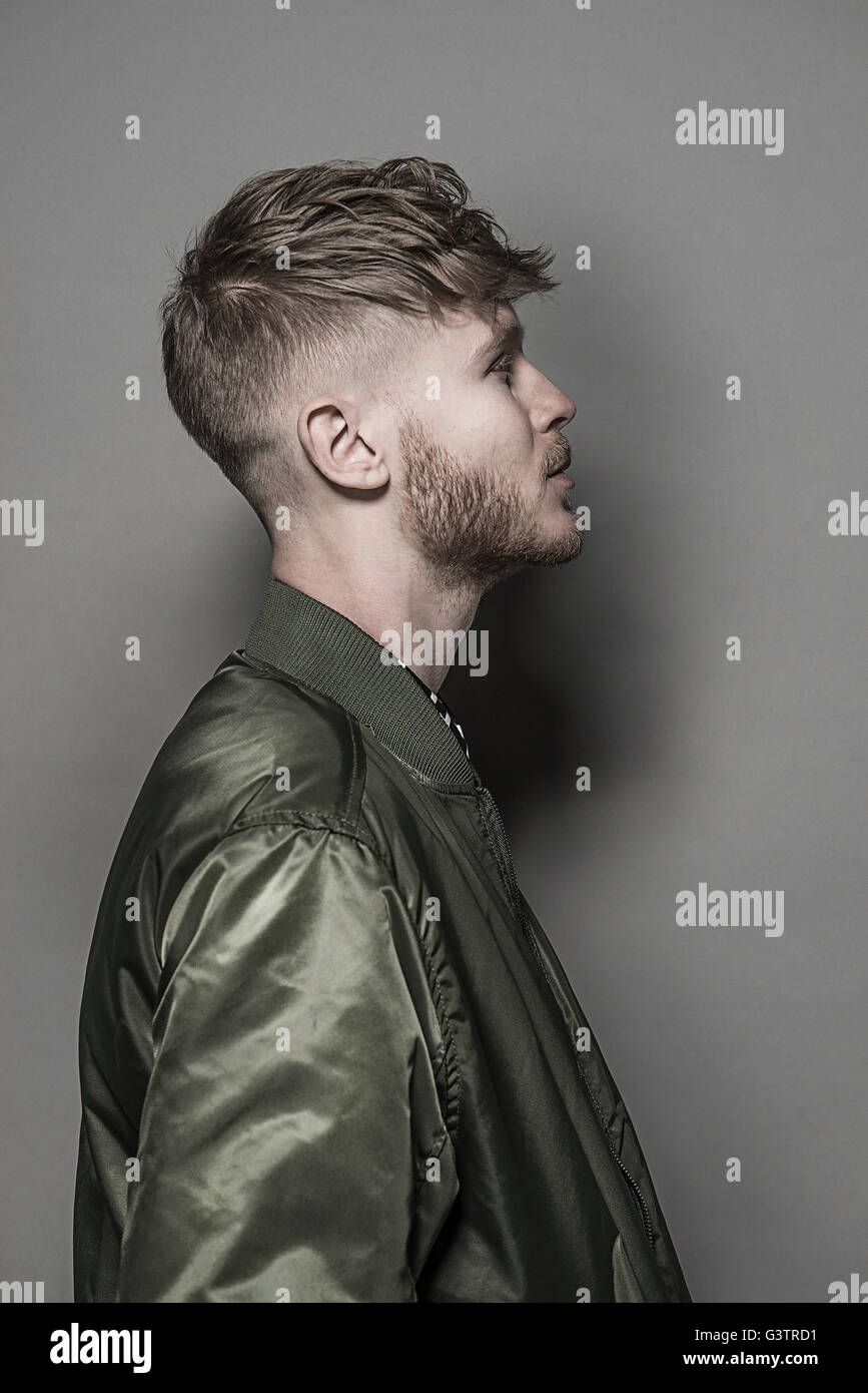 Studio portrait of a bearded young man wearing a green bomber jacket. Stock Photo