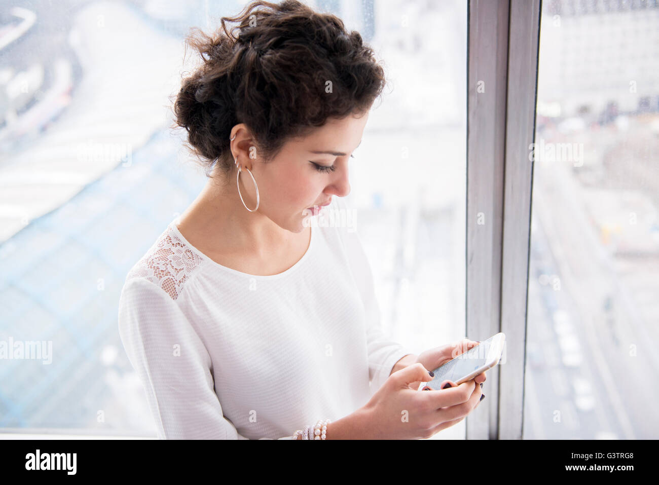 A professional woman looking at her phone in a high rise office block. Stock Photo