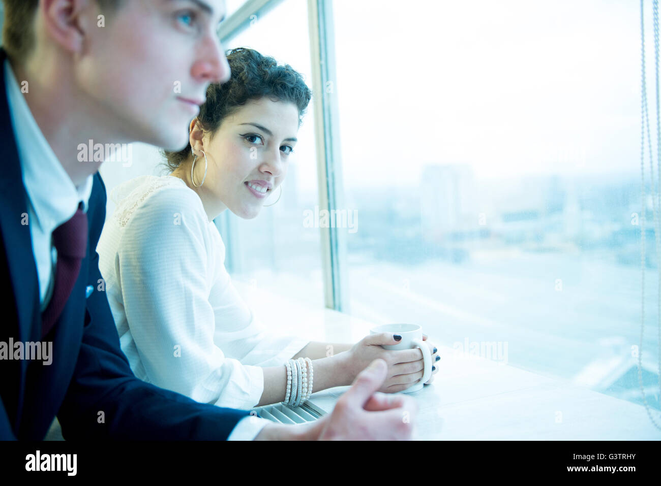 Two work colleagues standing at a window in an office block. Stock Photo