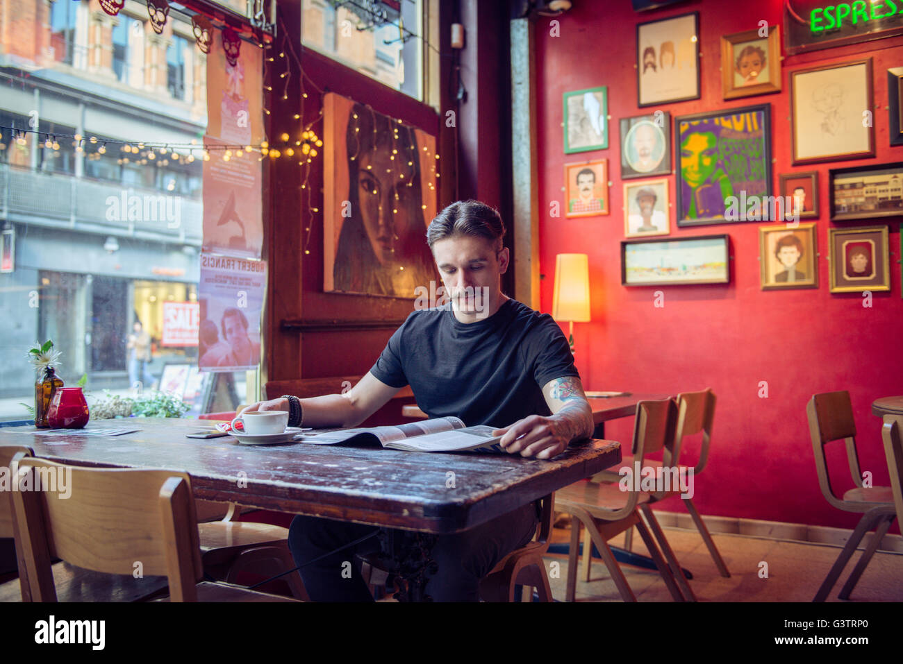 A young man sitting at a table in a coffee shop in Manchester. Stock Photo