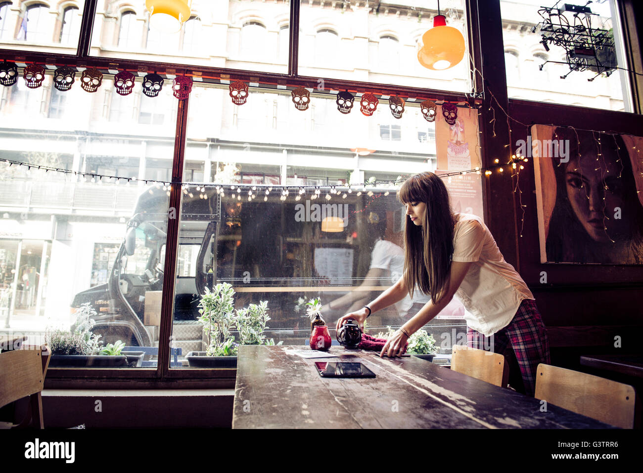 A young woman clearing a table in a coffee shop in Manchester. Stock Photo