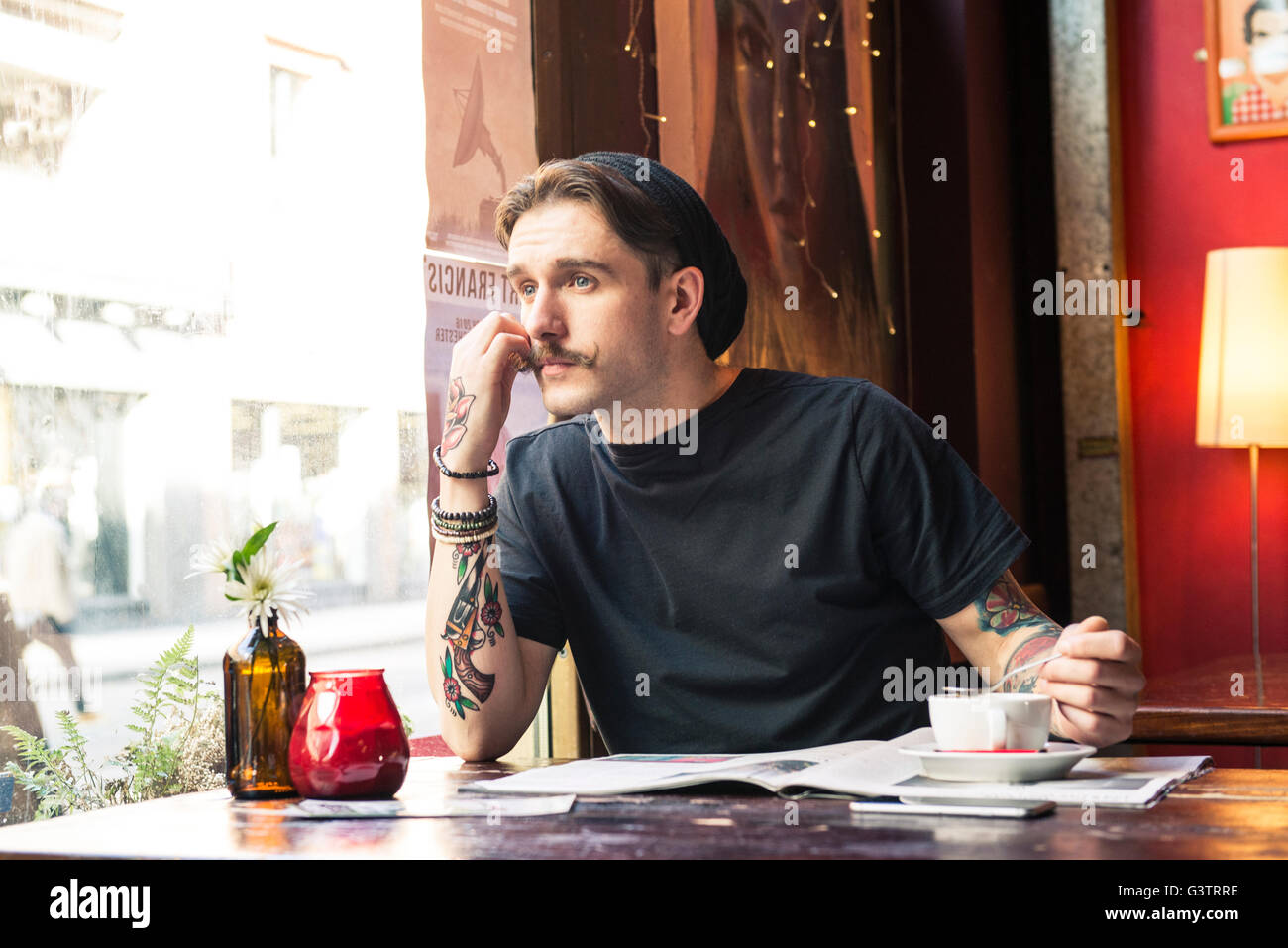 A young man sitting at a table in a coffee shop in Manchester. Stock Photo