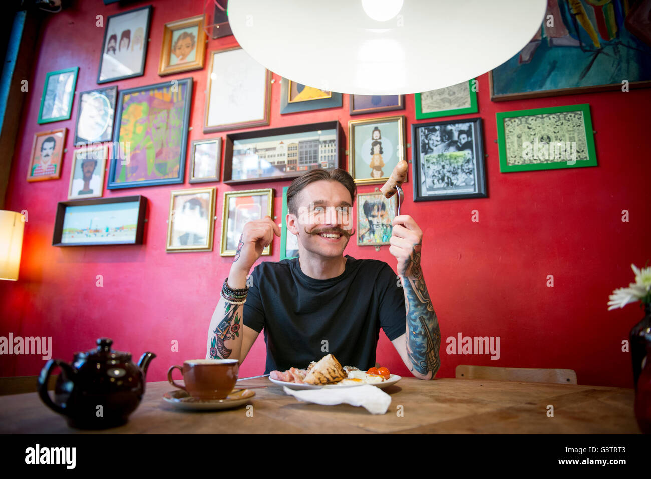 A young man eating at a table in a coffee shop in Manchester. Stock Photo
