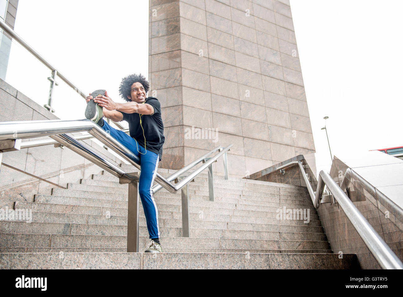 A young man limbering up for a jog along the South Bank in London. Stock Photo