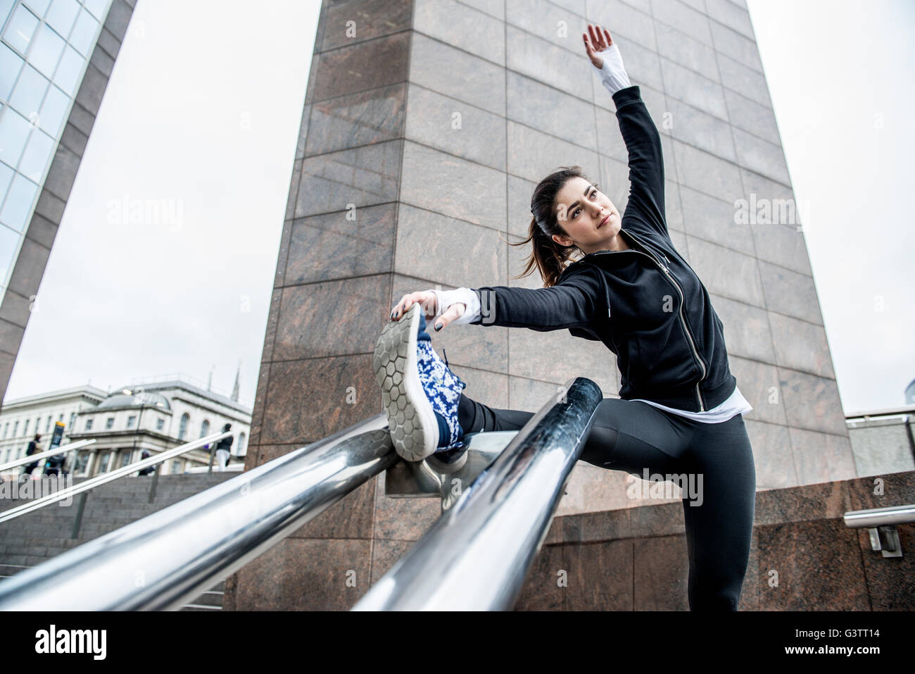 A young woman limbering up before a jog along the South Bank in London. Stock Photo