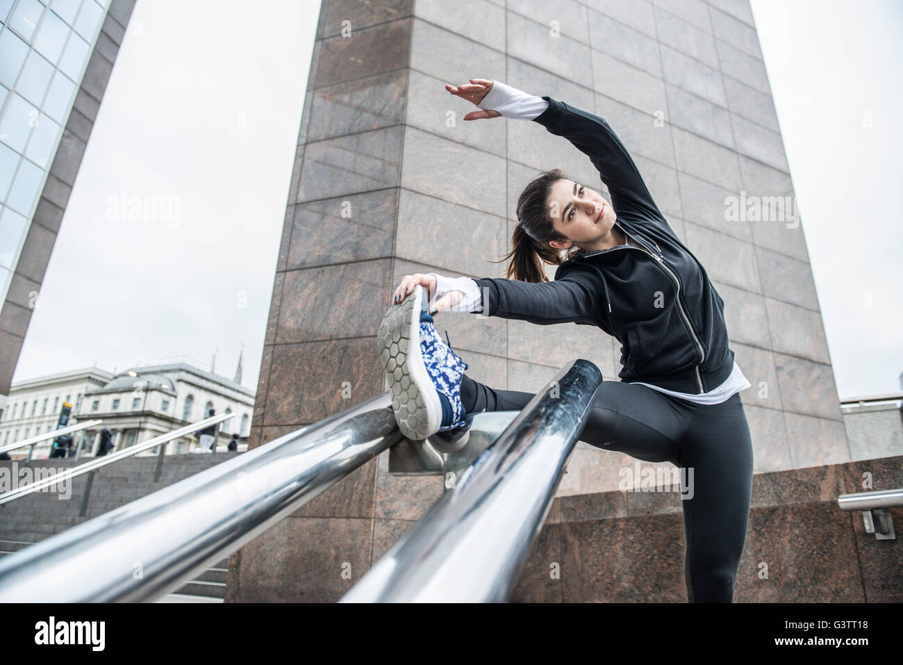 A young woman limbering up before a jog along the South Bank in London. Stock Photo