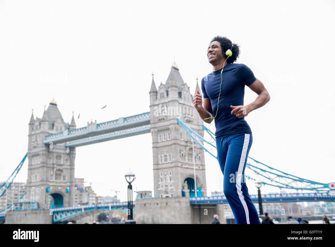 A young man jogging past Tower Bridge in London. Stock Photo