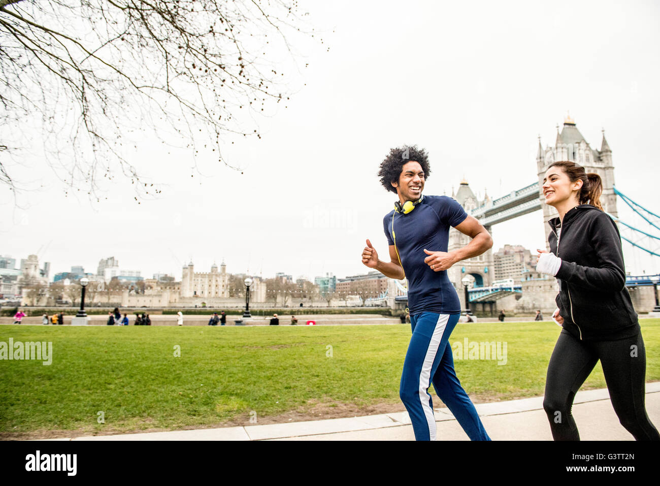 A young couple jogging together past Tower Bridge in London. Stock Photo