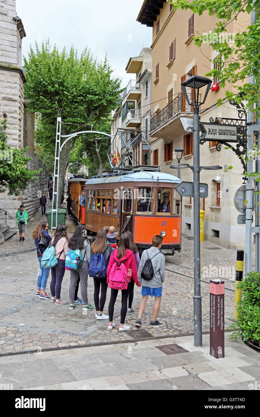 Young people watching tram from Port de Soller passing through Soller, Mallorca Stock Photo