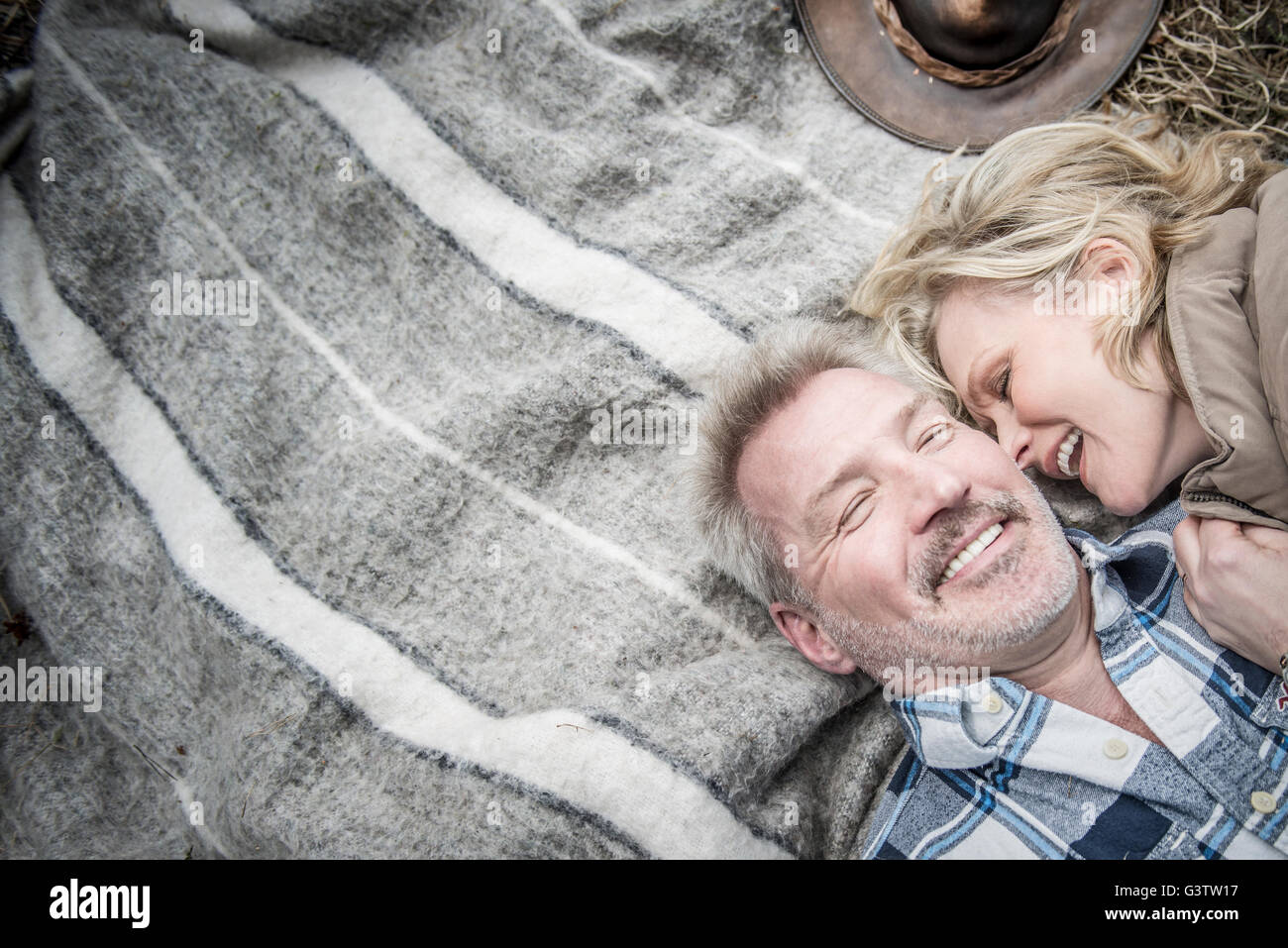 Senior couple cuddling together on a blanket at their campsite. Stock Photo