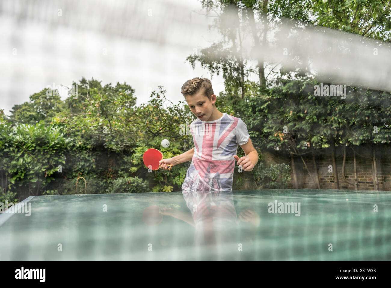 A twelve year old boy playing table tennis outside. Stock Photo