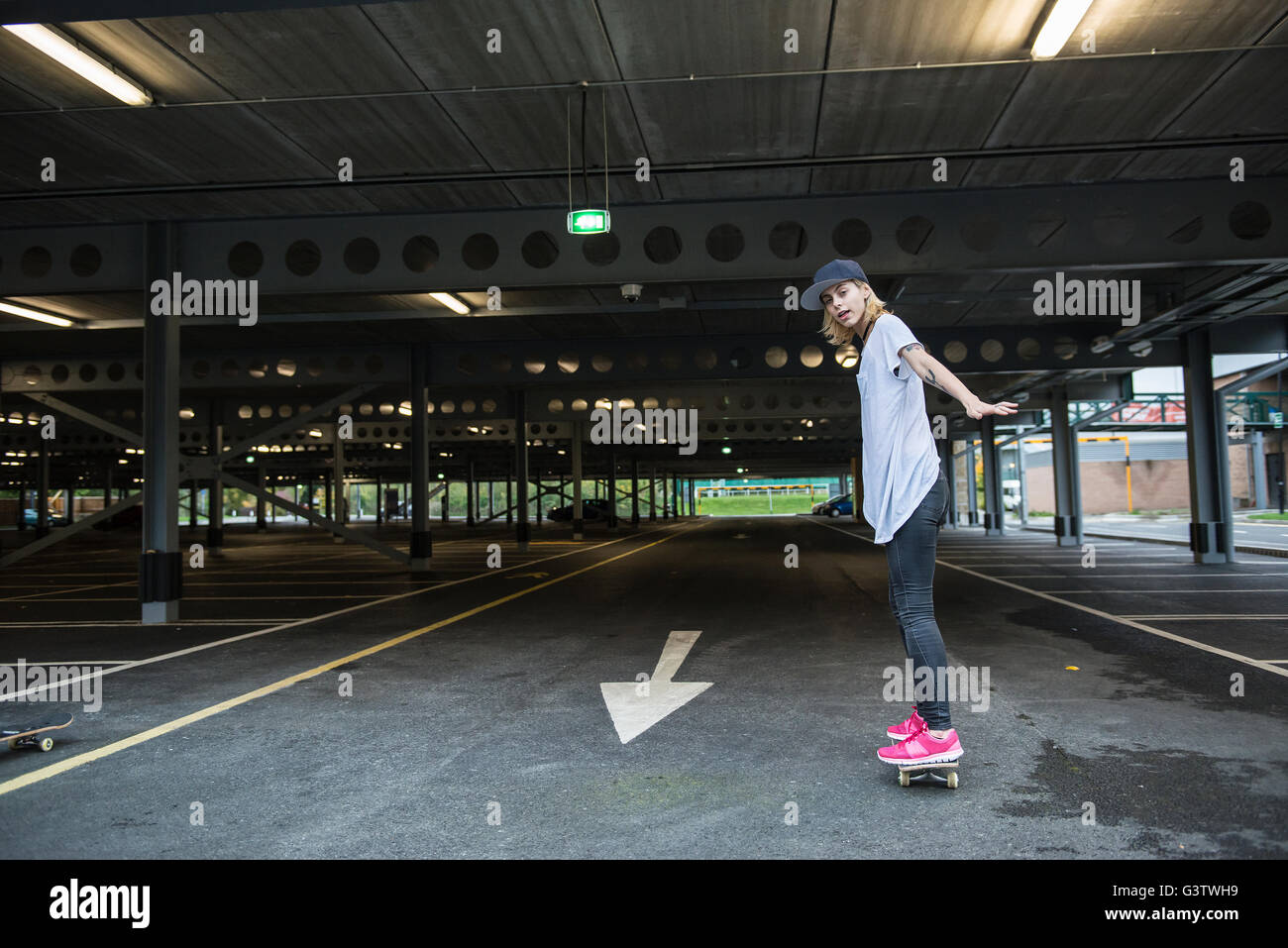 A cool young tattooed skater girl having fun with a skateboard. Stock Photo