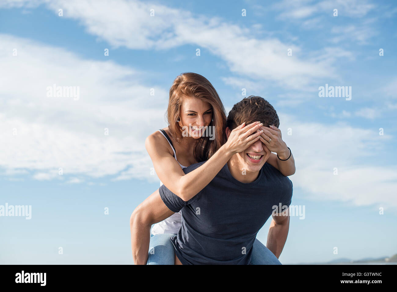 A young couple playing piggy back on the beach at Porthmadog. Stock Photo