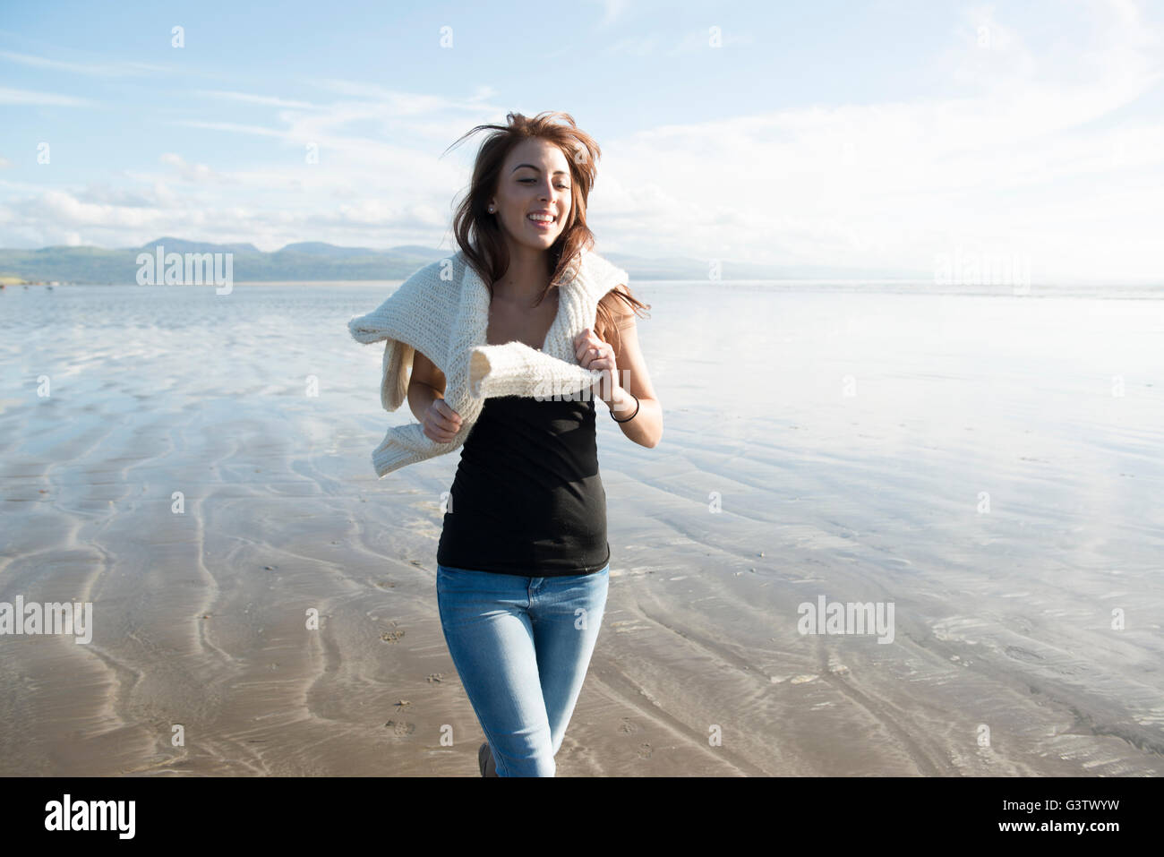 An attractive young woman enjoying the sunshine on the beach at Porthmadog. Stock Photo